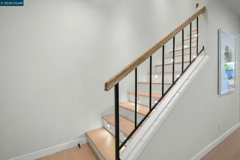 a view of staircase with wooden floor and white walls