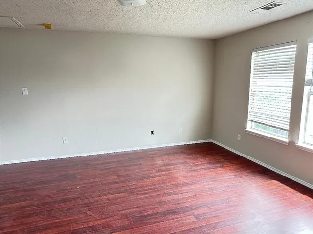 a view of an empty room and wooden floor and window