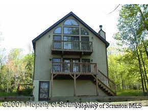2400 Crest View Road Lake Ariel, PA 18436 - Photo 1 of 9 a view of wooden house with a small yard and large trees