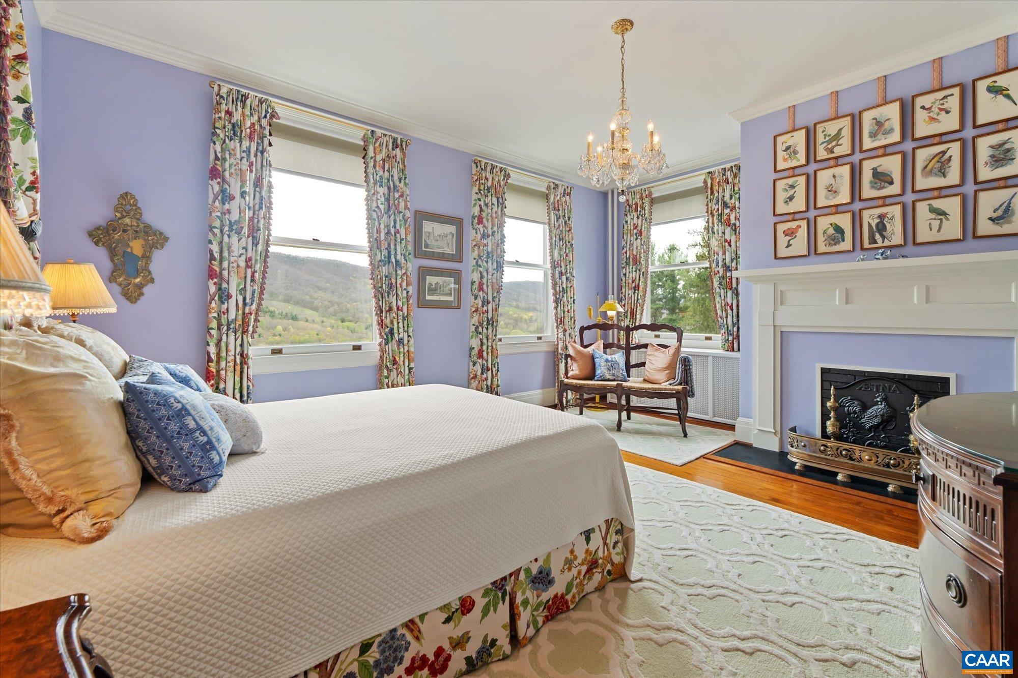 356 Routier Hill Road Hot Springs, VA 24445 - Photo 53 of 75 a bedroom with a bed a chandelier and a fireplace