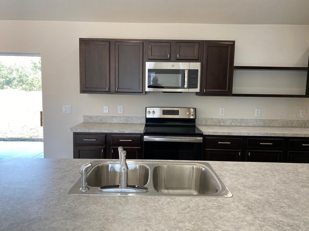 3331 Southwest 153rd Pl Road Ocala, FL 34473 - Photo 8 of 35 a kitchen with stainless steel appliances granite countertop a sink a stove a microwave and wooden cabinets