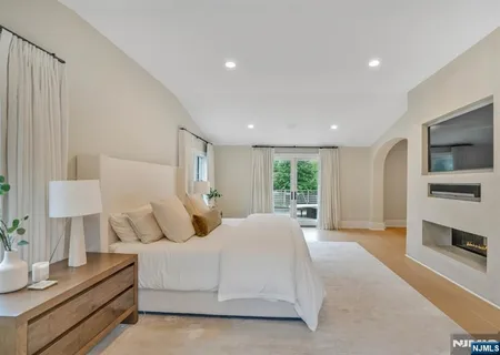 a bedroom with a large bed and a flat tv screen on dresser