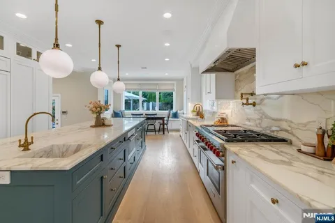 a kitchen with kitchen island granite countertop a stove a sink a center island and windows