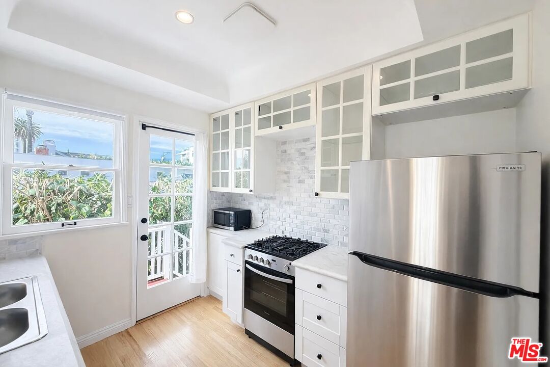 423 Ocean, Unit 2 Santa Monica, CA 90403 - Photo 11 of 18 a kitchen with stainless steel appliances granite countertop a refrigerator a sink a stove and white cabinets with wooden floor