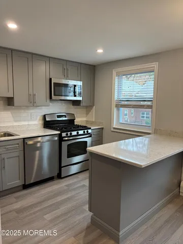 a kitchen with stainless steel appliances granite countertop a stove a sink and a microwave