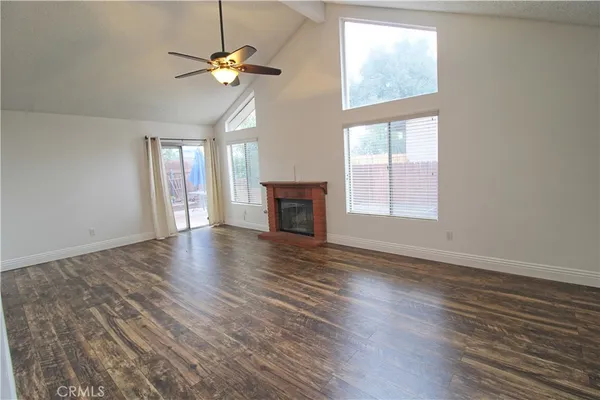 an empty room with wooden floor chandelier fan and windows