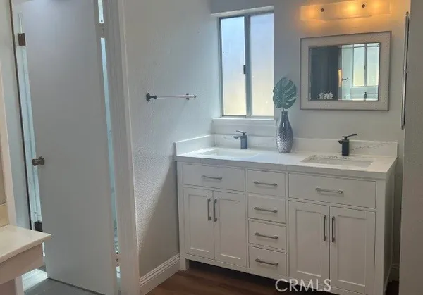a bathroom with a double vanity sink and mirror with toilet