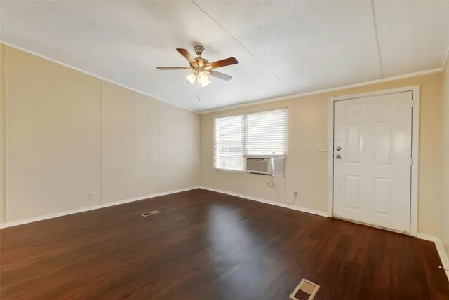 an empty room with wooden floor fan and windows