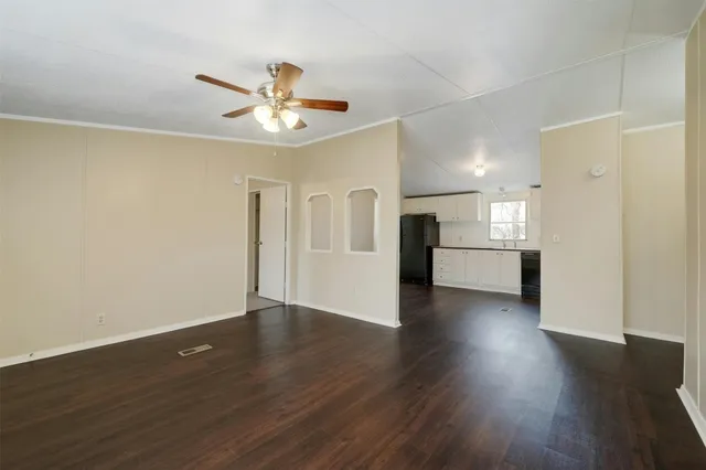 a view of an empty room with wooden floor and a ceiling fan