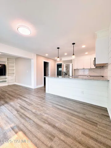 a view of a kitchen with kitchen island white cabinets and stainless steel appliances