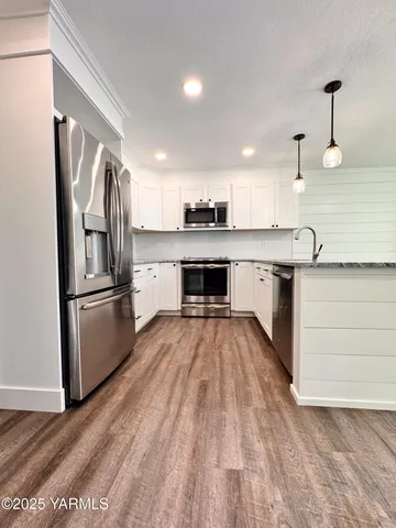 a kitchen with granite countertop a refrigerator and a stove top oven