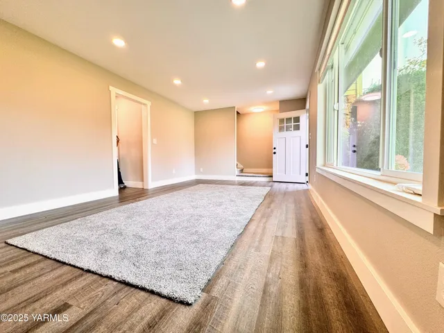 a view of a hall with wooden floor and a large window