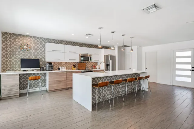 a kitchen with stainless steel appliances kitchen island granite countertop a table chairs and a refrigerator