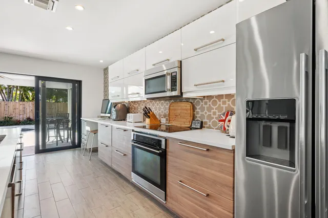 a kitchen with stainless steel appliances granite countertop a refrigerator a stove and a sink with large window