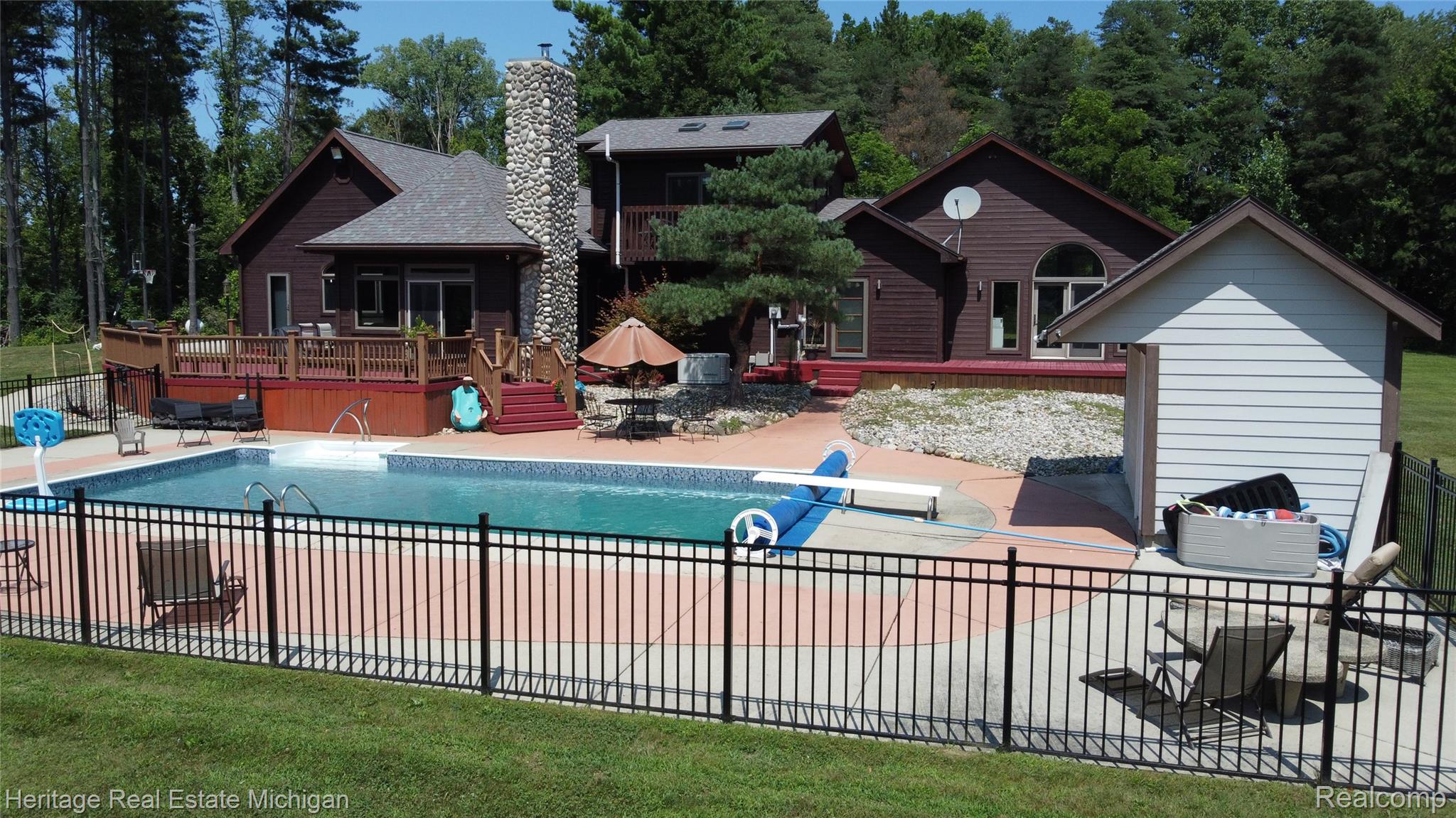 1888 Germany Road Williamston, MI 48895 - Photo 50 of 57 Expansive backyard featuring a large in-ground swimming pool, surrounding concrete patio, and black metal fencing
