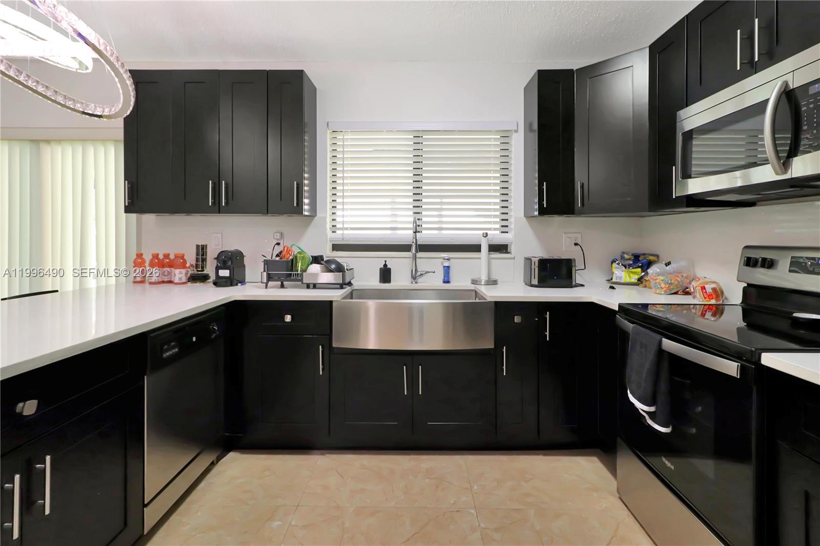 10940 Southwest 143rd Court Miami, FL 33186 - Photo 11 of 31 a kitchen with stainless steel appliances a sink dishwasher a stove a microwave oven and a refrigerator with wooden cabinets