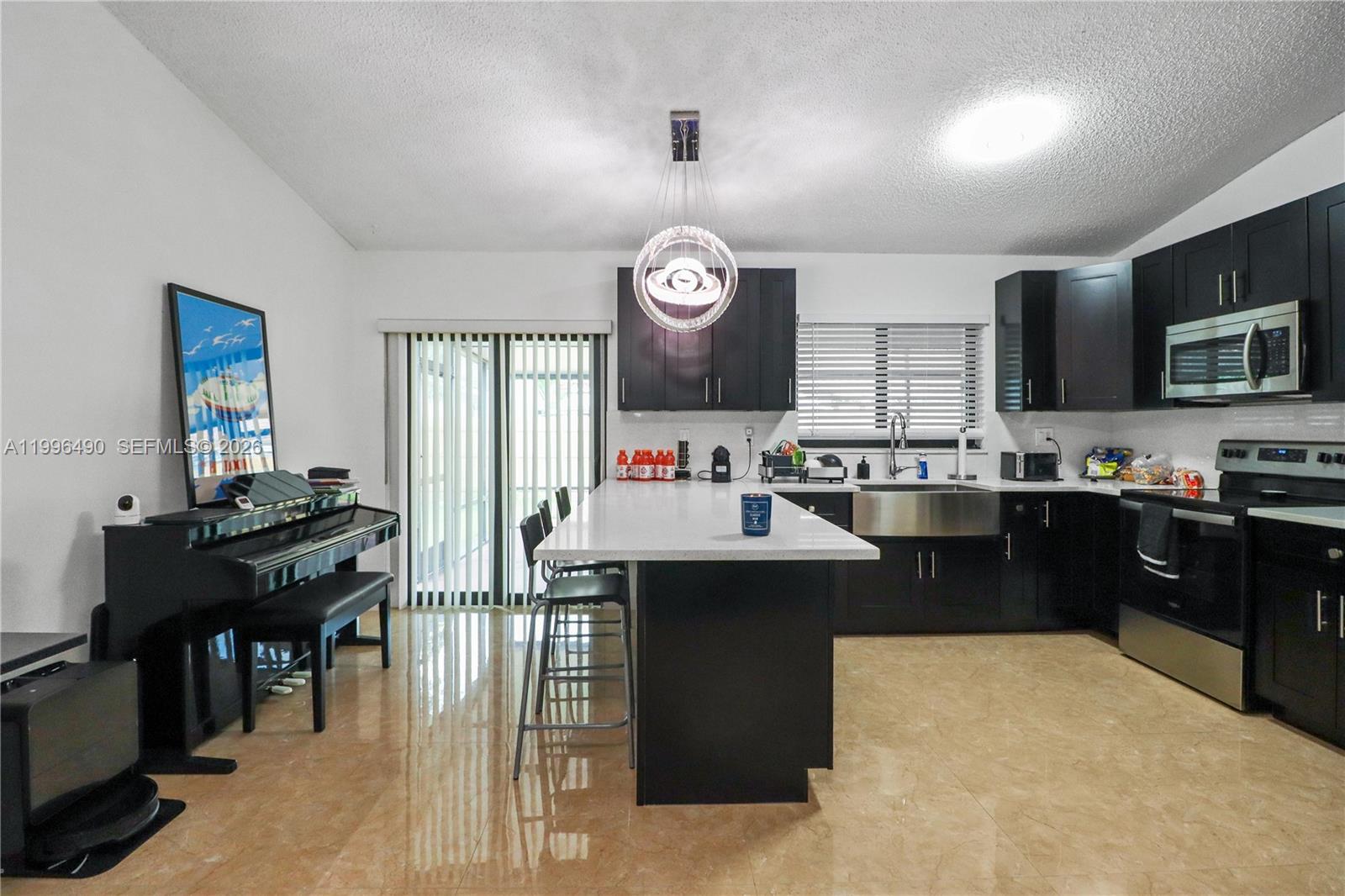10940 Southwest 143rd Court Miami, FL 33186 - Photo 8 of 31 a kitchen with granite countertop a stove top oven a sink dishwasher a dining table and chairs with wooden floor