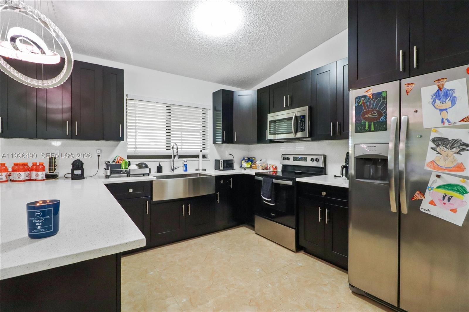 10940 Southwest 143rd Court Miami, FL 33186 - Photo 10 of 31 a kitchen with stainless steel appliances kitchen island granite countertop a refrigerator a sink dishwasher a stove and a dining table with wooden floor