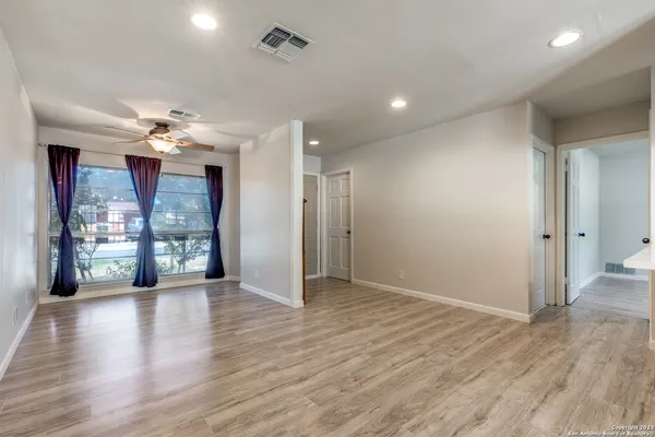 a view of an empty room with window and wooden floor