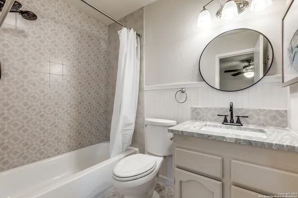 a bathroom with a granite countertop toilet sink and mirror