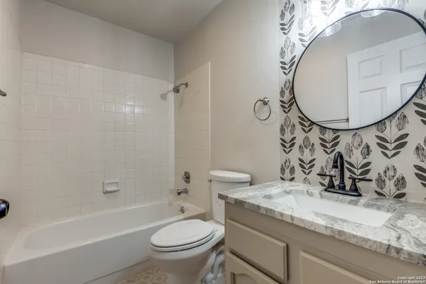 a bathroom with a granite countertop sink a toilet and bathtub