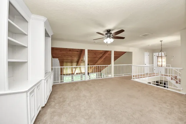 an empty room with windows and ceiling fan