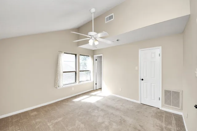 an empty room with windows and ceiling fan