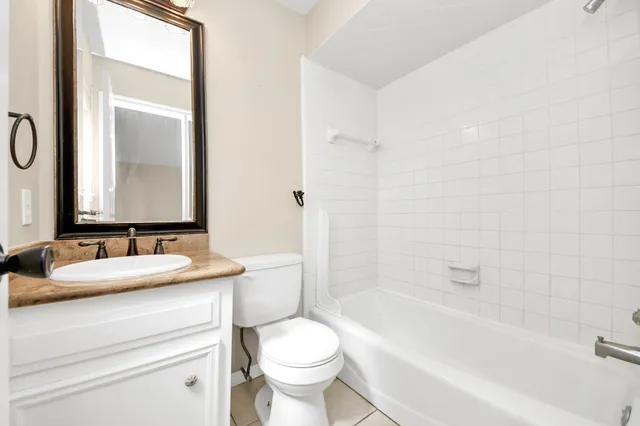 a bathroom with a granite countertop sink toilet mirror and bathtub