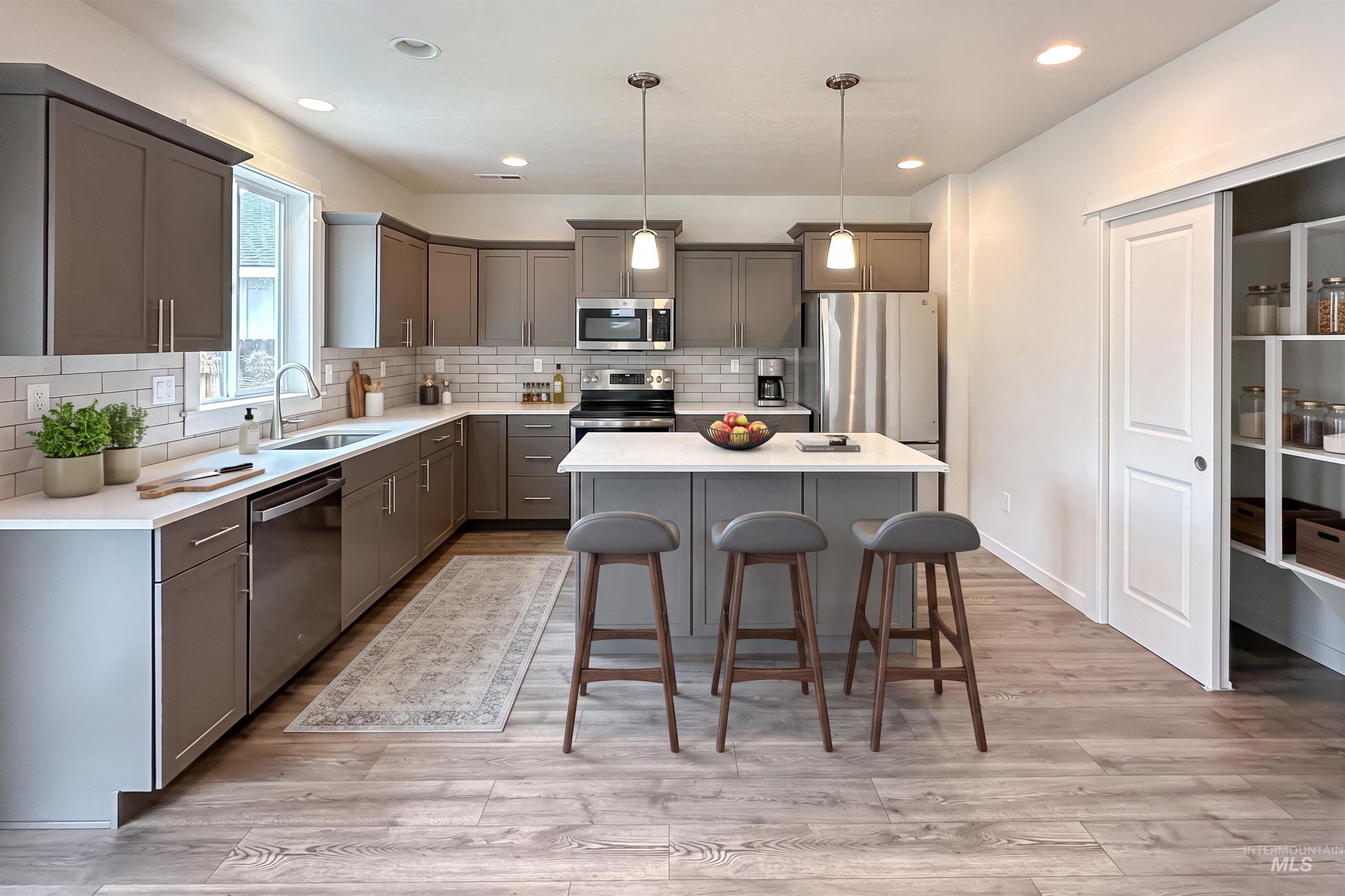 9687 West Arnold Road Boise, ID 83714 - Photo 8 of 37 Kitchen featuring a central island, stainless steel appliances, pendant lighting, built-in pantry shelving, and wood-finish flooring