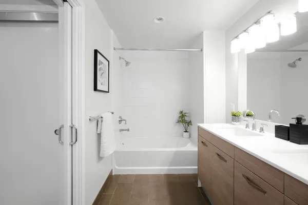 a bathroom with a tub sink shower and a mirror
