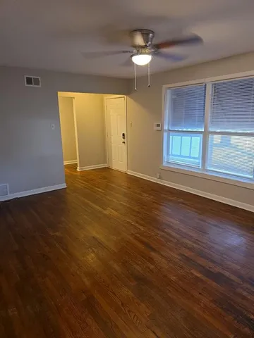 an empty room with wooden floor chandelier and windows