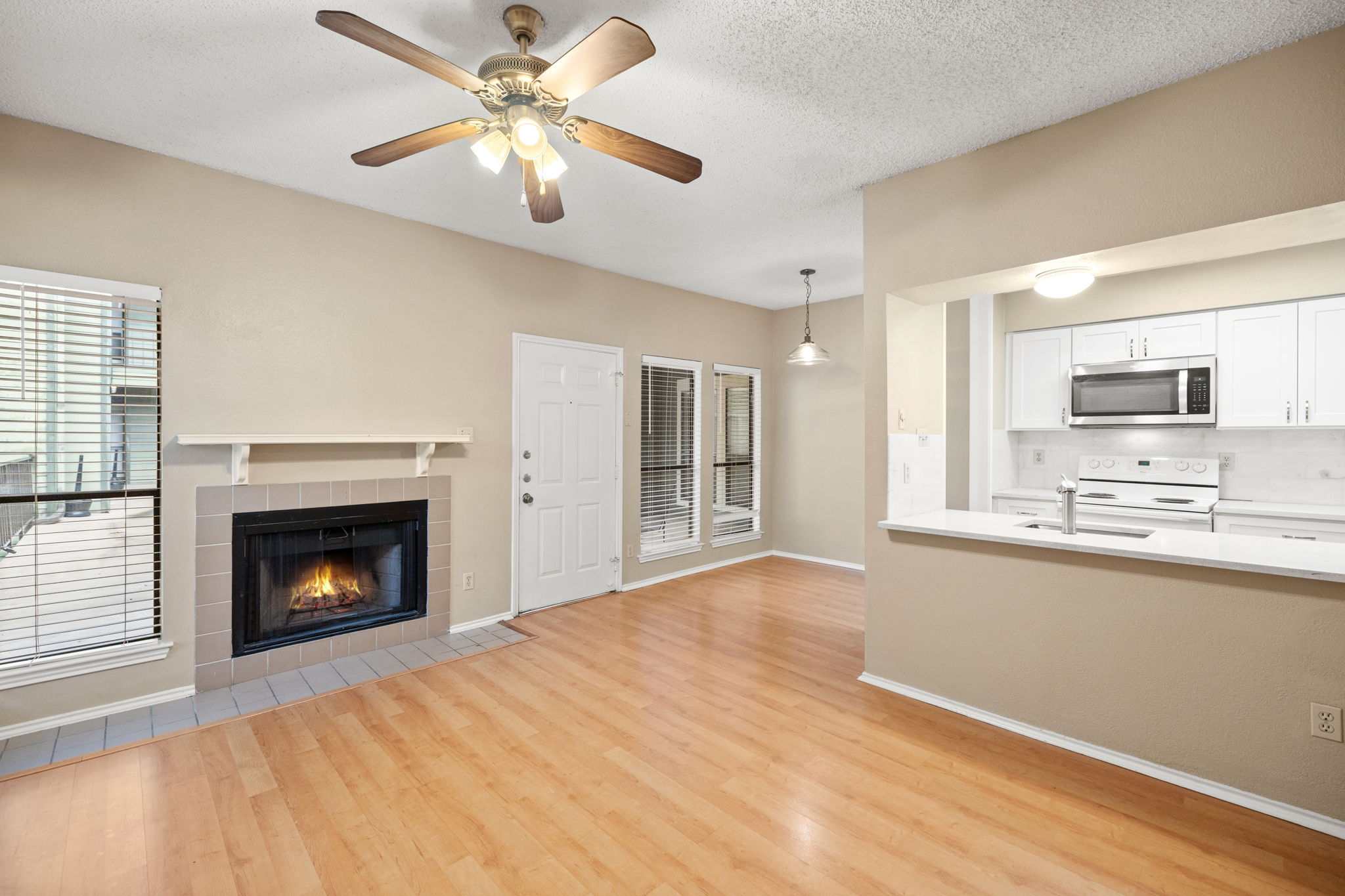 2706 Salado Street, Unit 210 Austin, TX 78705 - Photo 9 of 32 a view of a kitchen with a fireplace a ceiling fan and wooden floor