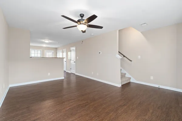 a view of an empty room with wooden floor and a ceiling fan