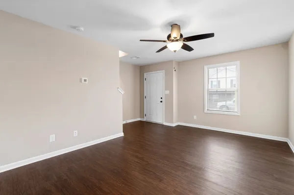 a view of an empty room with wooden floor and a window