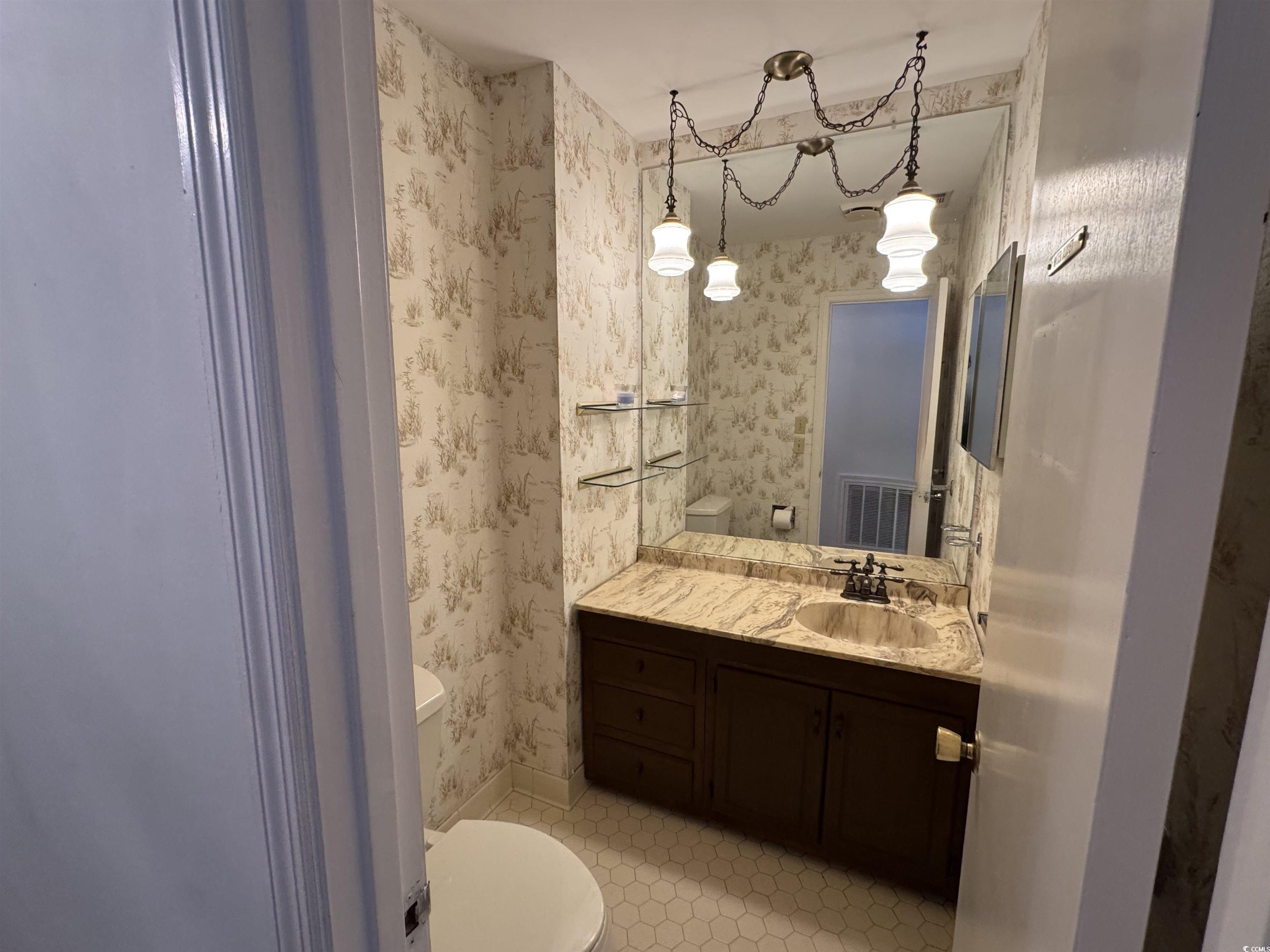 58 Wedgefield Village Road, Unit 48 Georgetown, SC 29440 - Photo 11 of 23 Half bathroom featuring wallpapered walls and vanity