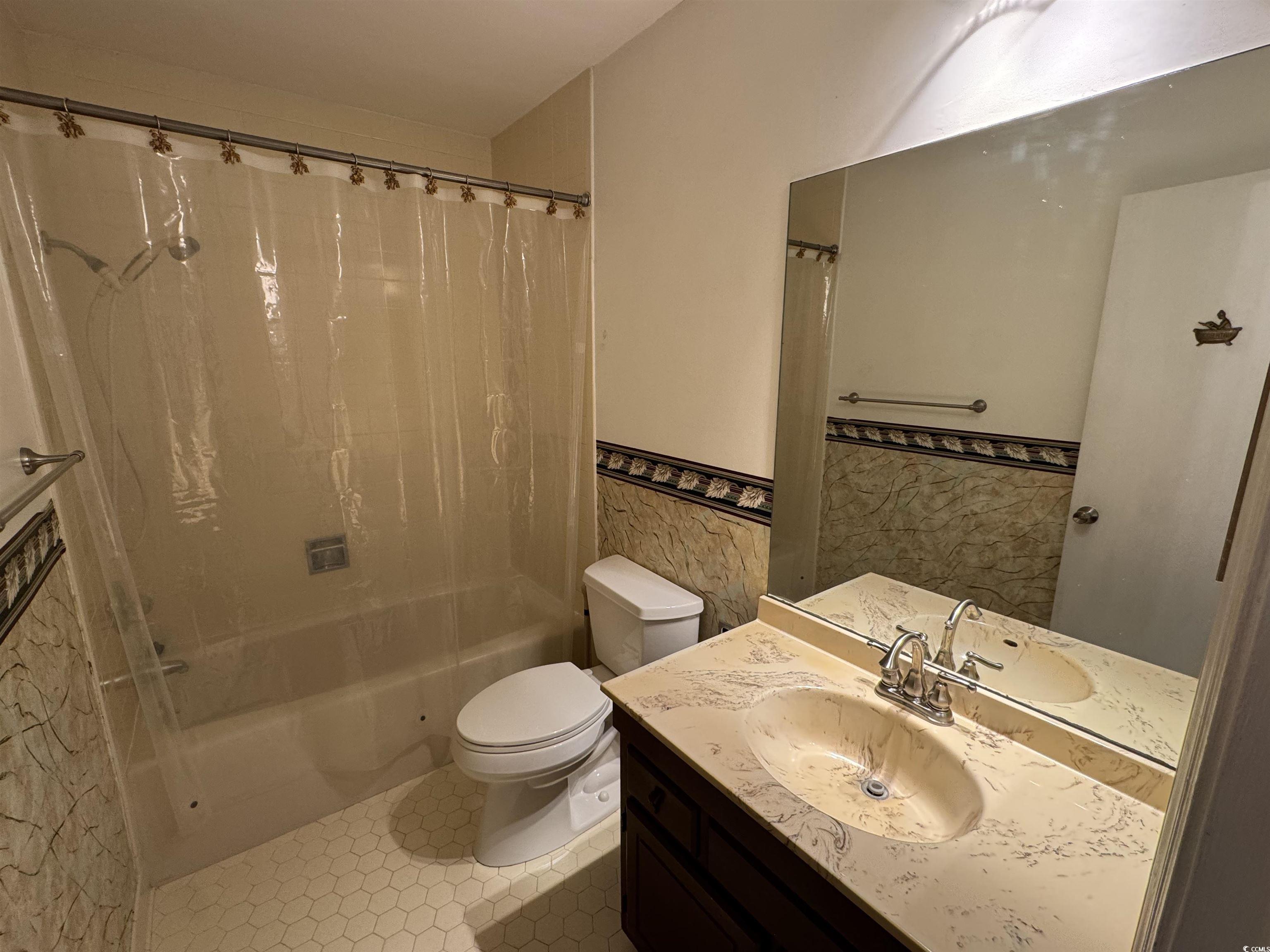 58 Wedgefield Village Road, Unit 48 Georgetown, SC 29440 - Photo 12 of 23 Bathroom featuring shower / bath combination with curtain, vanity, wainscoting, and tile walls