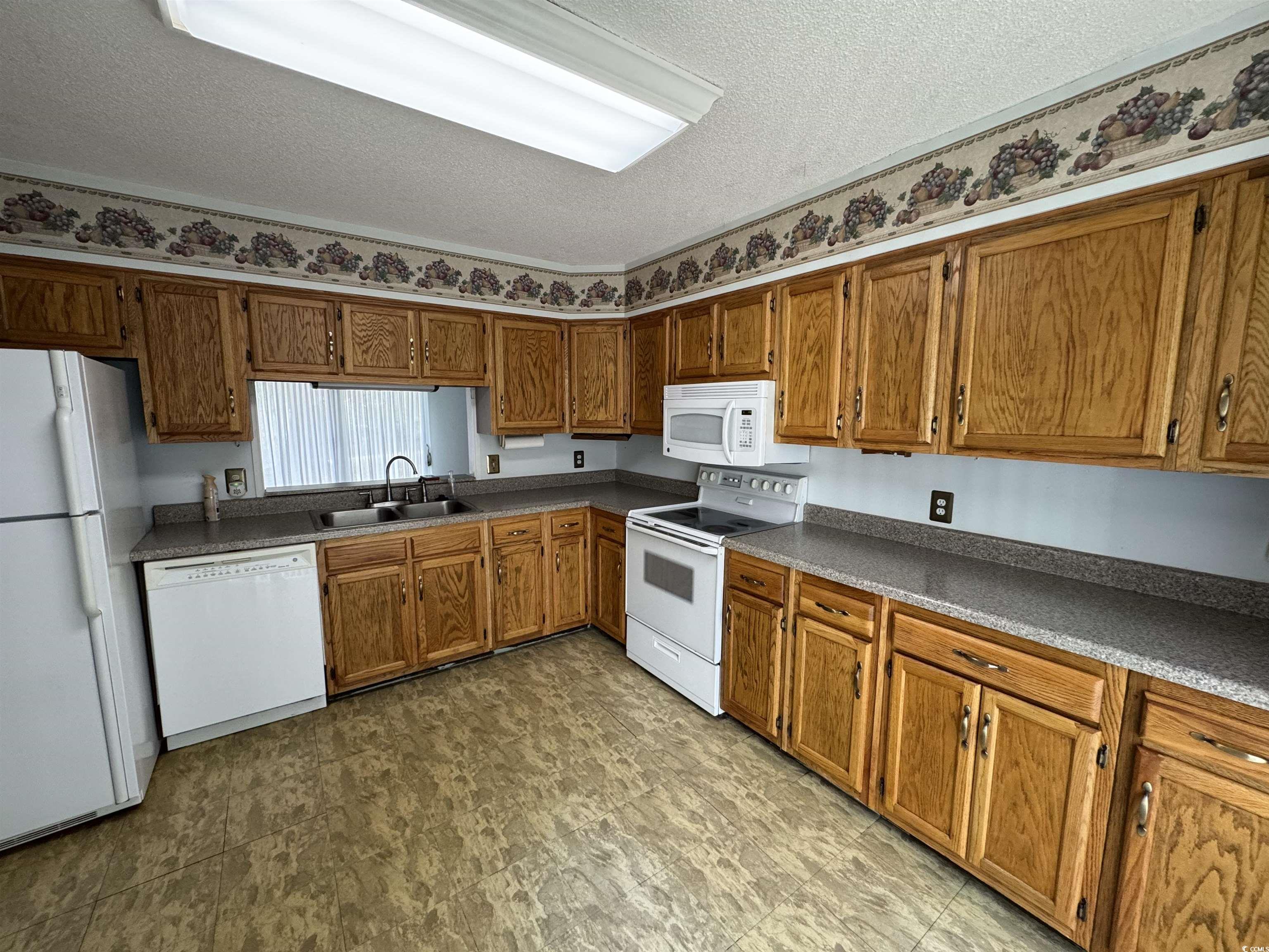 58 Wedgefield Village Road, Unit 48 Georgetown, SC 29440 - Photo 13 of 23 Kitchen with white appliances, a textured ceiling, brown cabinets, and dark countertops