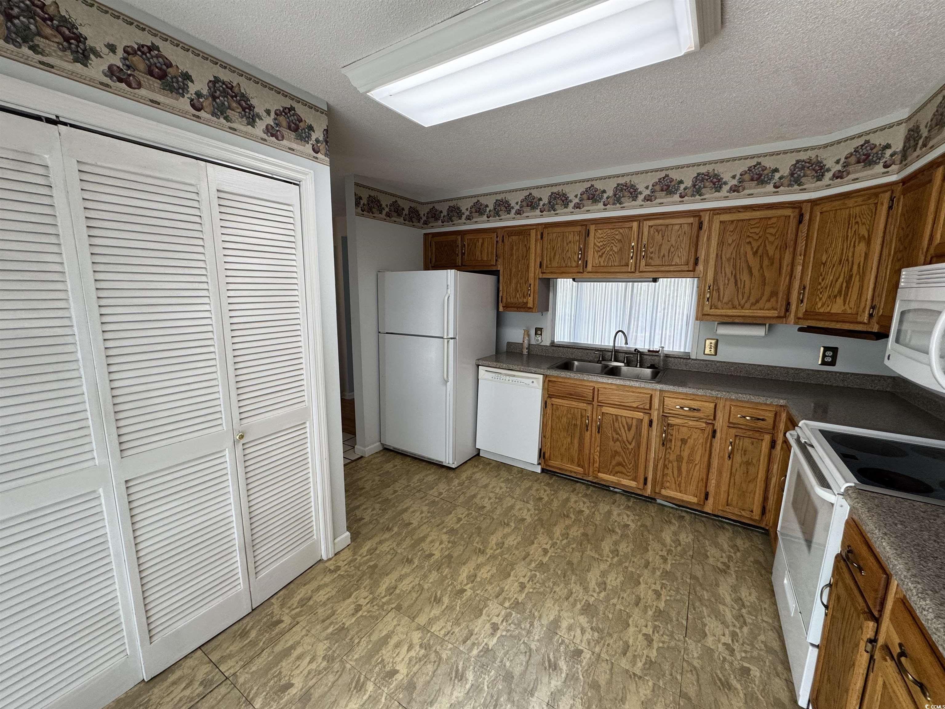 58 Wedgefield Village Road, Unit 48 Georgetown, SC 29440 - Photo 14 of 23 Kitchen with a textured ceiling, white appliances, dark countertops, and brown cabinets