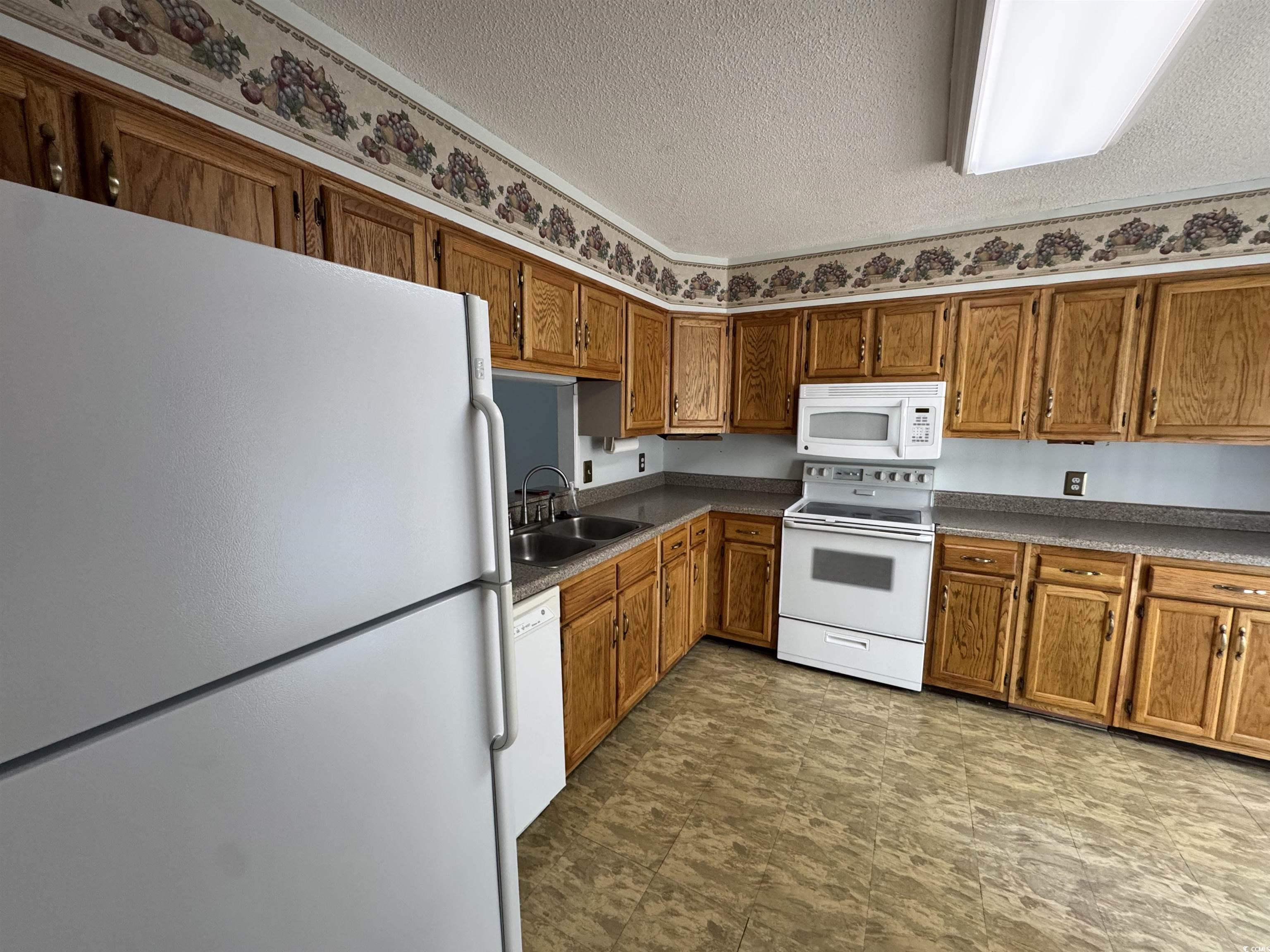 58 Wedgefield Village Road, Unit 48 Georgetown, SC 29440 - Photo 15 of 23 Kitchen featuring white appliances, a textured ceiling, brown cabinets, and dark countertops