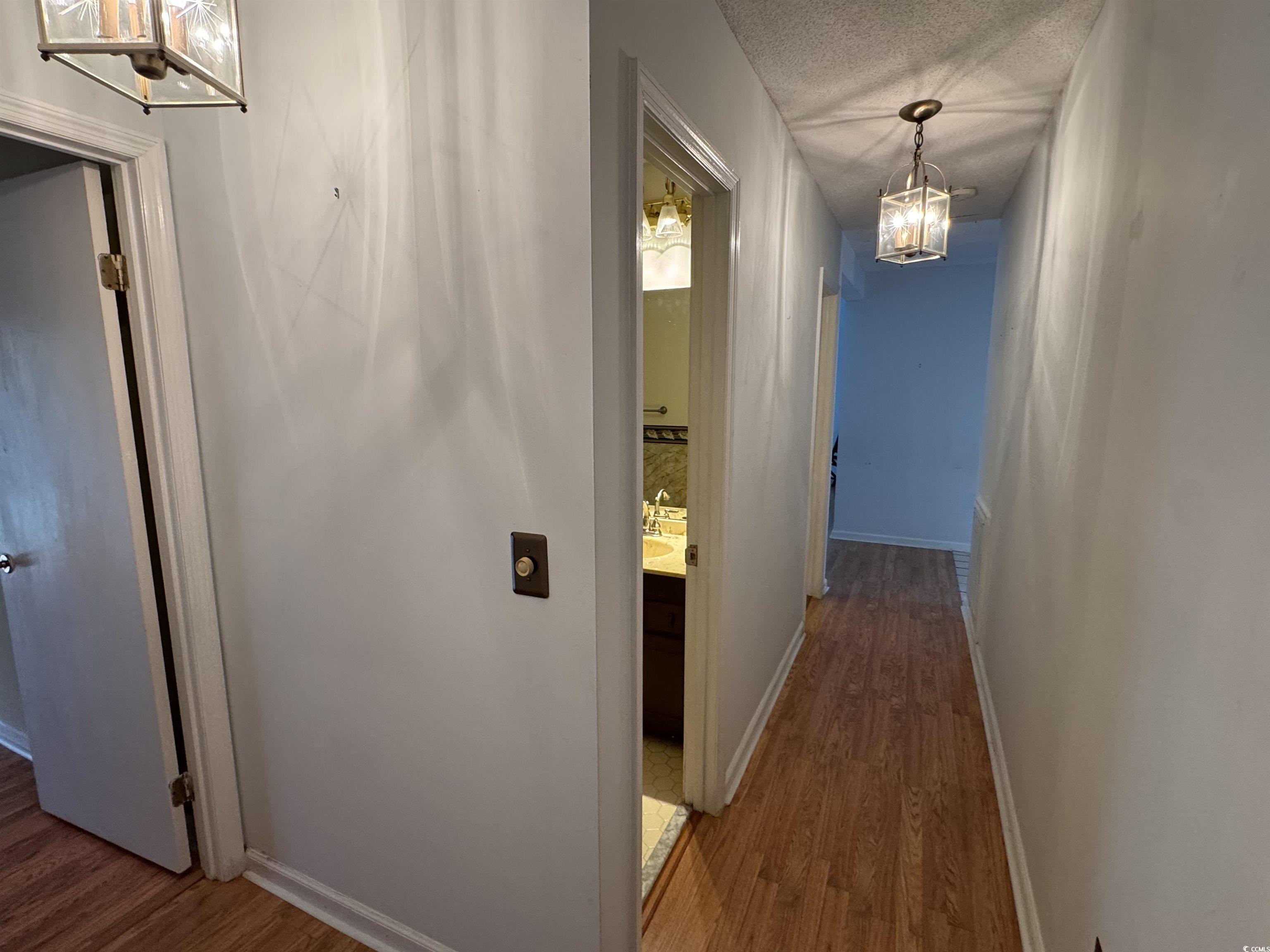 58 Wedgefield Village Road, Unit 48 Georgetown, SC 29440 - Photo 16 of 23 Corridor featuring a chandelier, dark wood-type flooring, and a textured ceiling