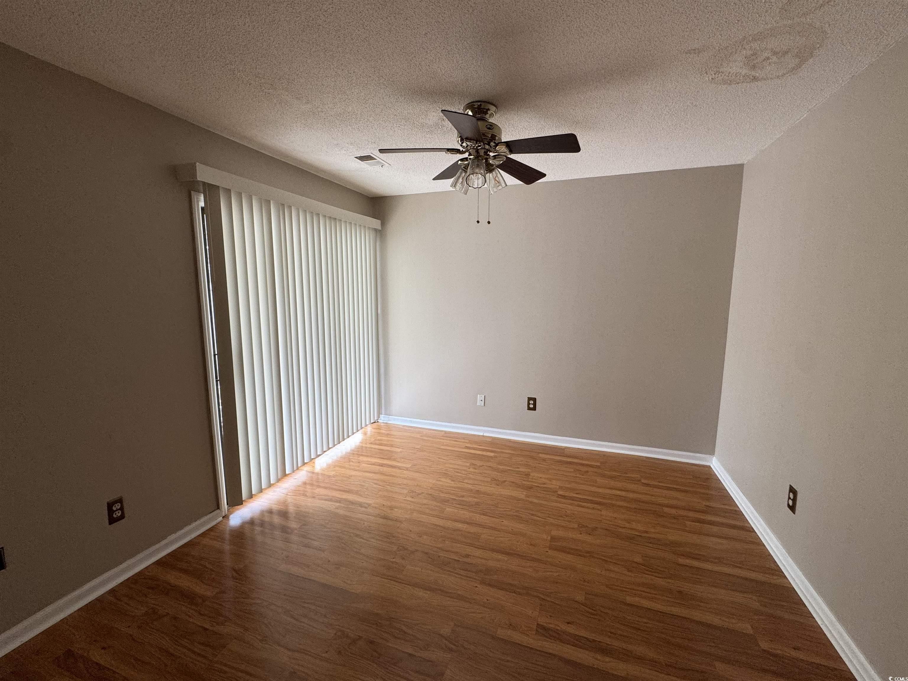 58 Wedgefield Village Road, Unit 48 Georgetown, SC 29440 - Photo 6 of 23 Empty room featuring dark wood-style floors, a ceiling fan, and a textured ceiling