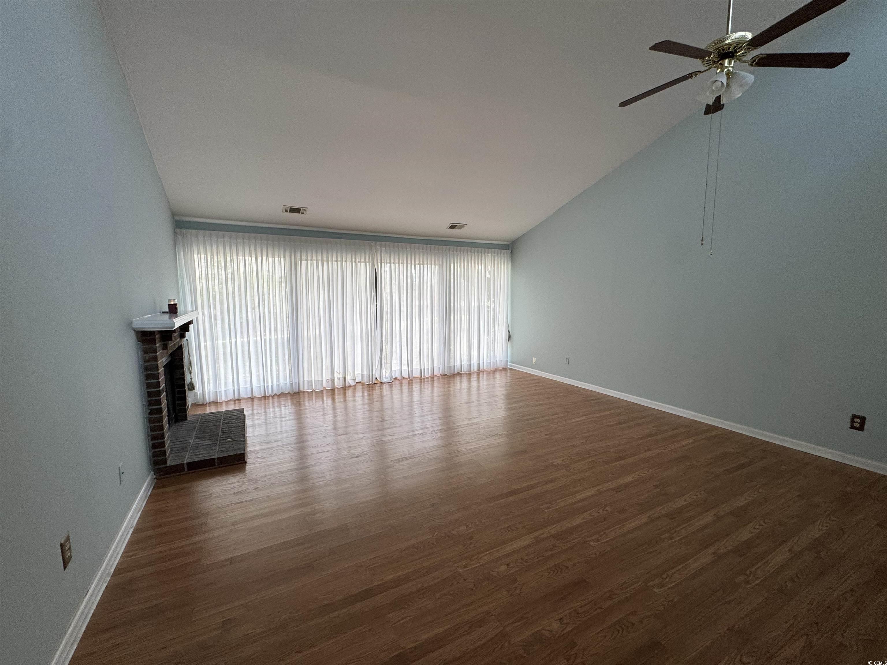 58 Wedgefield Village Road, Unit 48 Georgetown, SC 29440 - Photo 8 of 23 Unfurnished living room with dark wood-style floors, a fireplace, and lofted ceiling