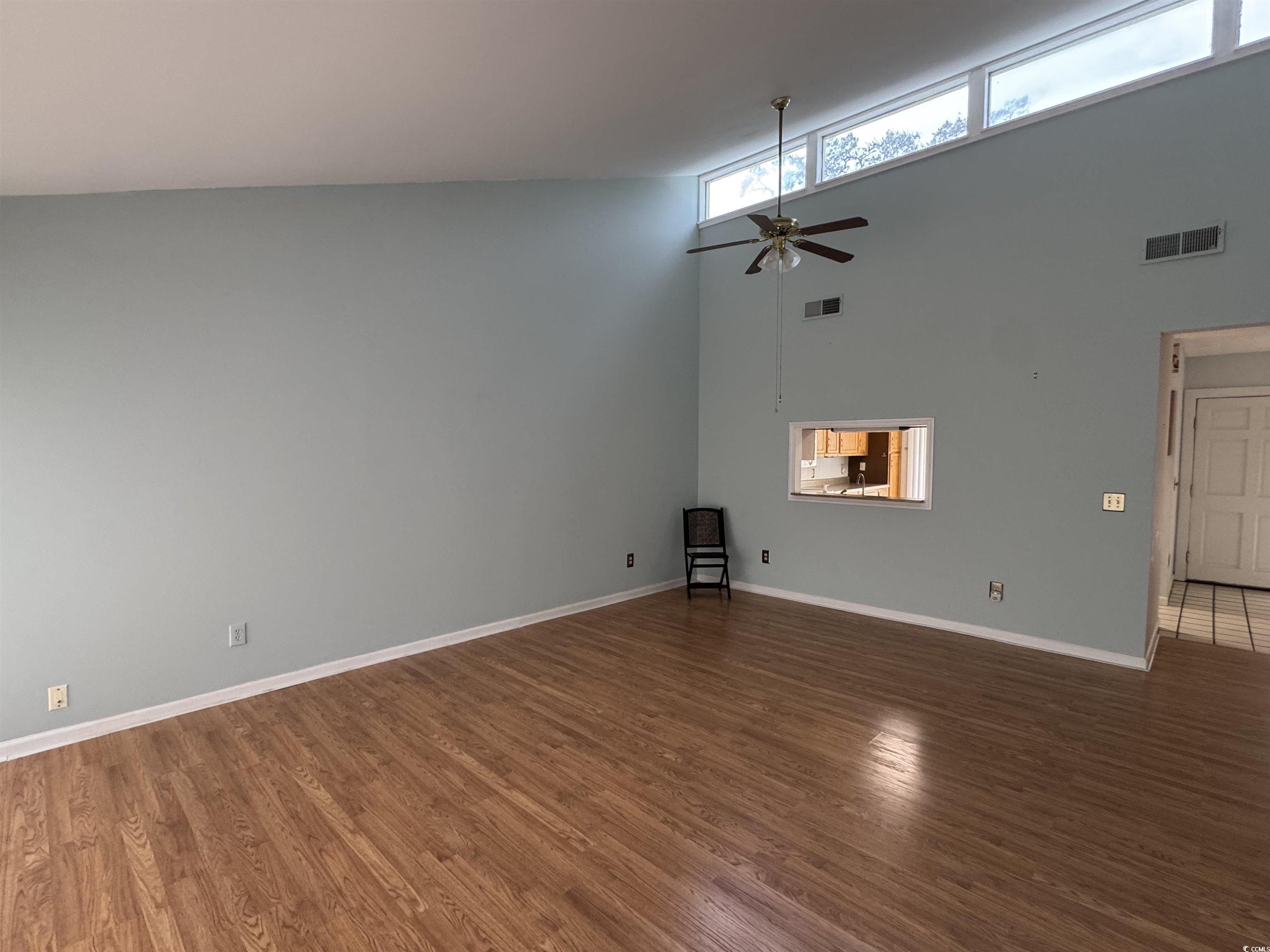 58 Wedgefield Village Road, Unit 48 Georgetown, SC 29440 - Photo 9 of 23 Unfurnished living room with a high ceiling, healthy amount of natural light, a ceiling fan, and dark wood-style floors