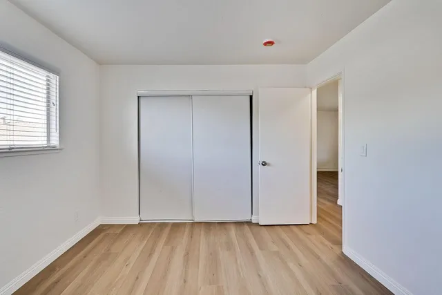 a view of an empty room with closet and a window