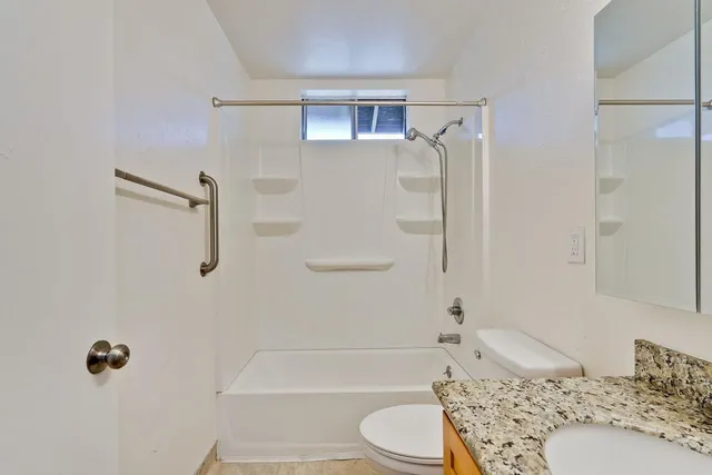 a bathroom with a bathtub shower sink vanity and toilet