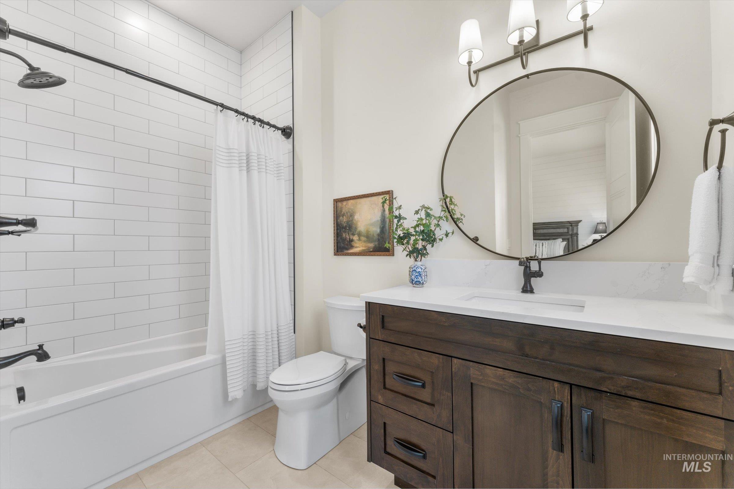 6585 South Pemberley Way Meridian, ID 83642 - Photo 33 of 43 Bathroom featuring a white subway tile shower surround, dark wood-finish vanity with an integrated sink, white countertop, and a circular mirror