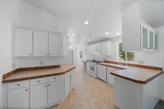a kitchen with stainless steel appliances granite countertop a sink and white cabinets