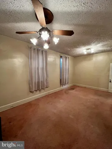 an empty room with stairs and fan