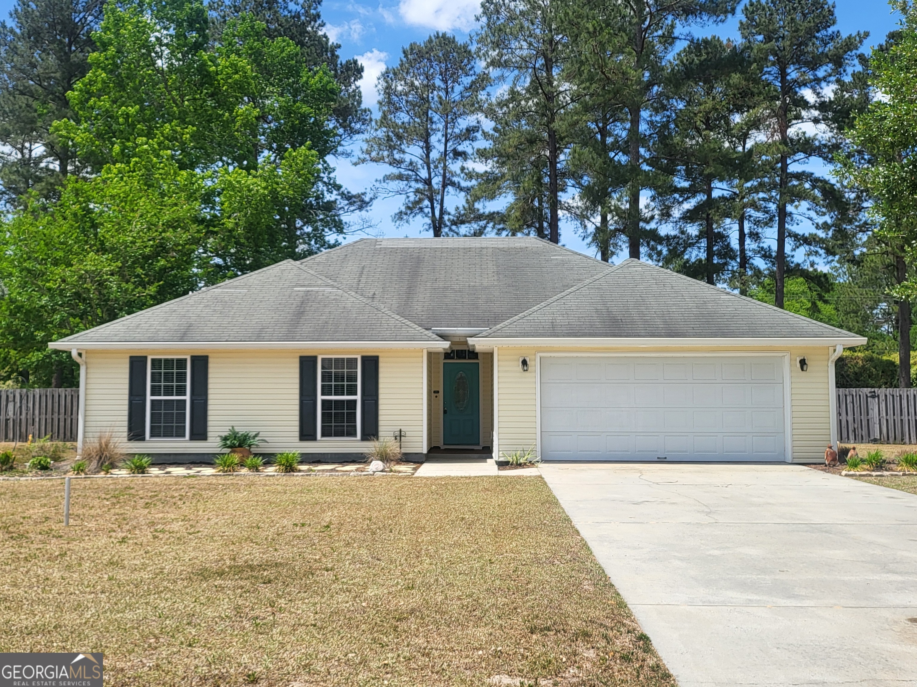 a front view of house with yard and trees in the background