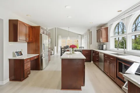 a large kitchen with kitchen island a sink stove and wooden cabinets
